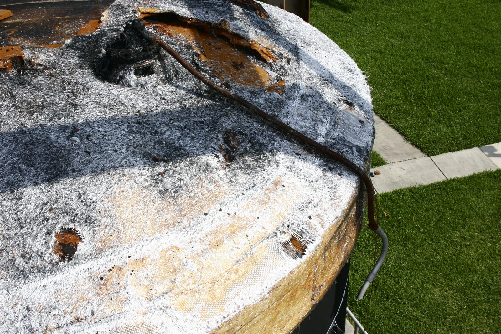Charred fiberglass tank surface examined during a fire cause and origin investigation